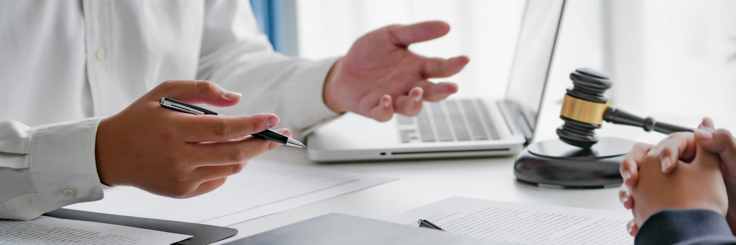 Entretien entre un conseiller juridique et un client dans un bureau, avec ordinateur portable et maillet de juge sur le bureau